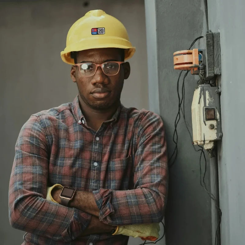 Person wearing a yellow hard hat and plaid shirt in an industrial setting