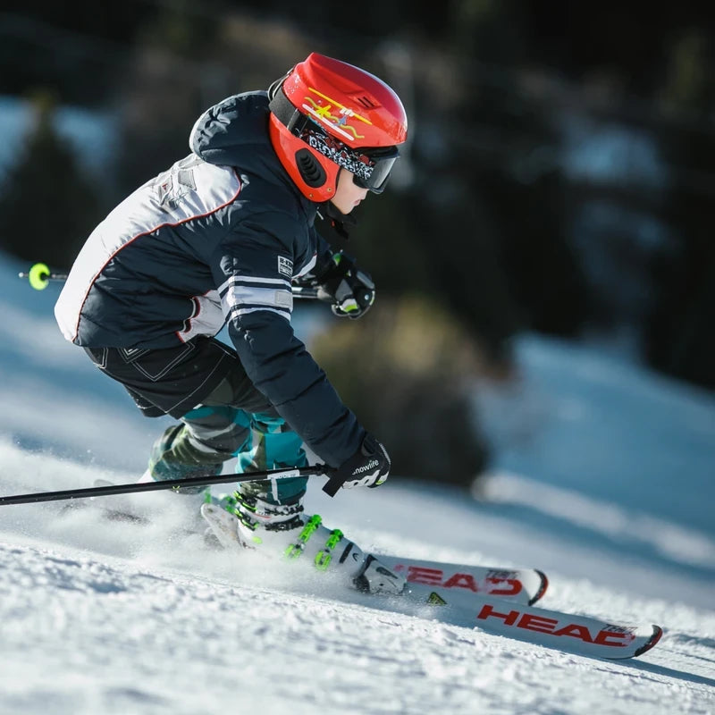 Skier in action with a red helmet and black and white jacket on a snowy slope.